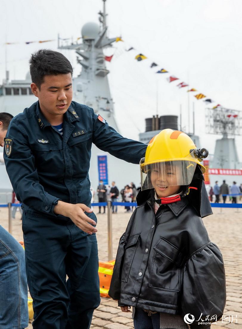 4月23日，山東青島港，海軍成立紀念日艦艇開放活動現場，海軍士兵向小朋友講解如何使用穿戴防護服。