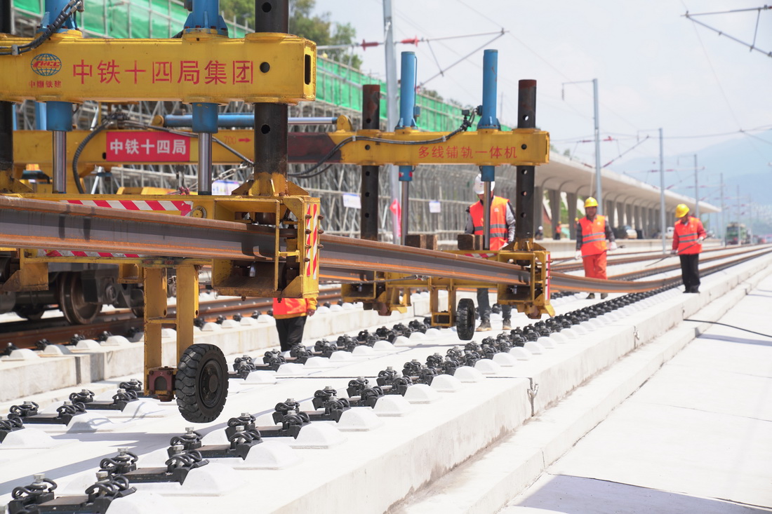4月26日，在昌景黃高鐵浮梁東站施工現場，工作人員利用機械將鋼軌放入承軌槽。