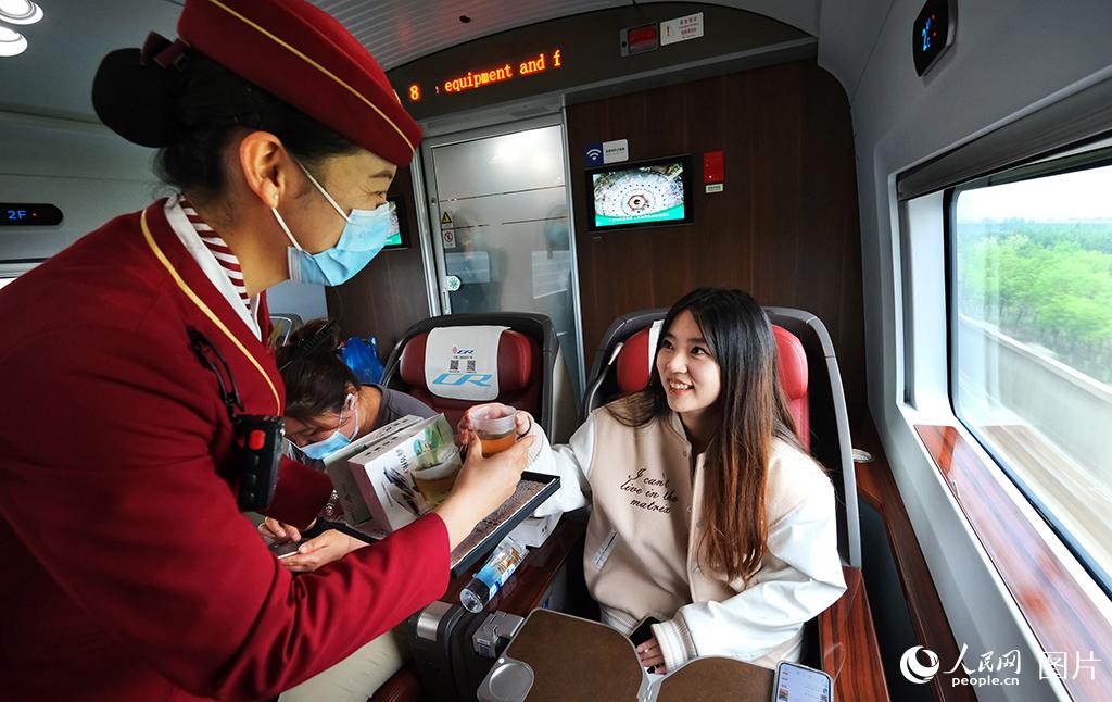 5月3日，铁路天津客运段京津城际C2027次乘务员正在为旅客进行送水服务。杨宝森摄