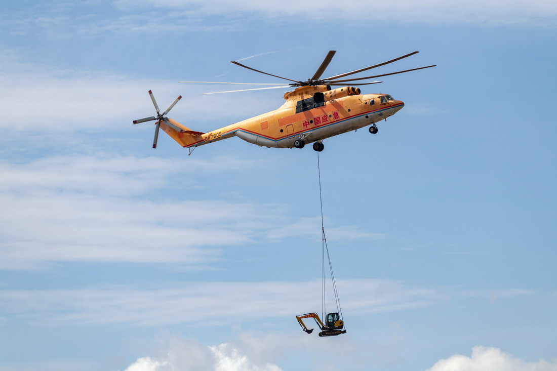 5月16日，一架参演直升机在丽江演习现场上空转运一台挖掘机。