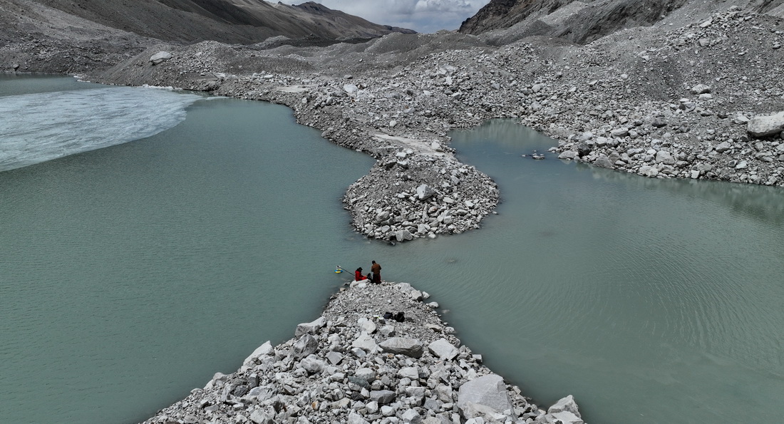 在珠峰海拔約5300米處的冰前湖，科考隊員在取水樣（5月12日攝，無人機照片）。新華社記者 晉美多吉 攝