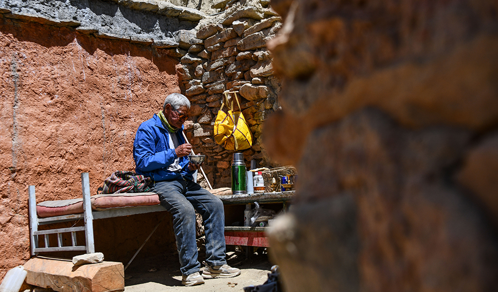 仁增旺扎老人在石窟旁吃午饭（5月26日摄）。新华社记者 晋美多吉 摄