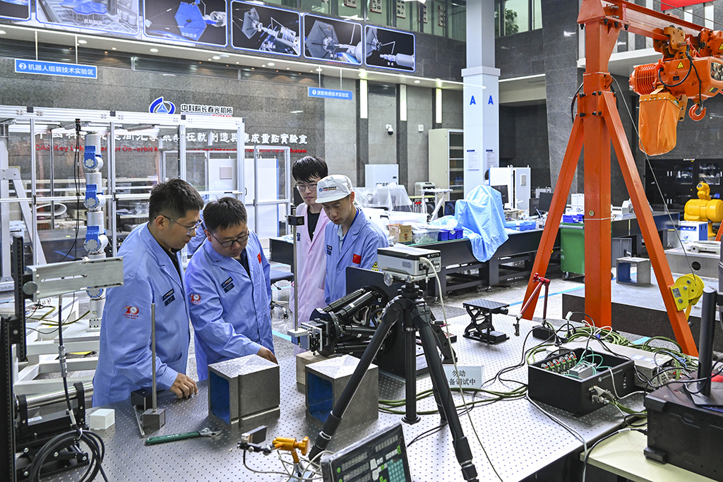 中国科学院空间光学系统在轨制造与集成重点实验室副主任徐振邦（左二）与同事在实验室内讨论科研工作（5月25日摄）。新华社记者 许畅 摄