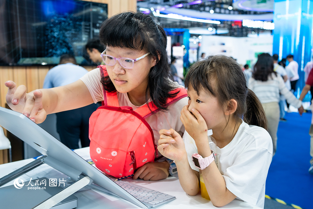 5月27日，在贵州贵阳的2023 中国国际大数据产业博览会上，小朋友正在体验现场展品。人民网 阳茜摄