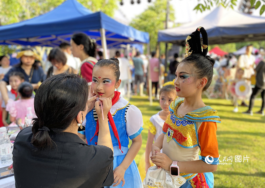 5月26日，武汉市东湖高新区花山街道白羊山社区联合举办以“‘童’心协力 共创未来”为主题的六一儿童节文艺汇演。图为演出现场，小朋友们排队补妆。人民网记者 关喜艳摄