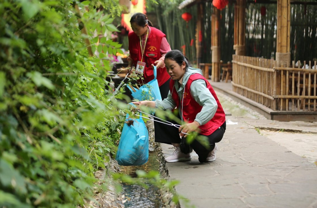 6月3日，在山東省臨沂市沂南縣竹泉村景區，參加志願環保活動的志願者在撿拾垃圾。新華社發（王彥冰攝）