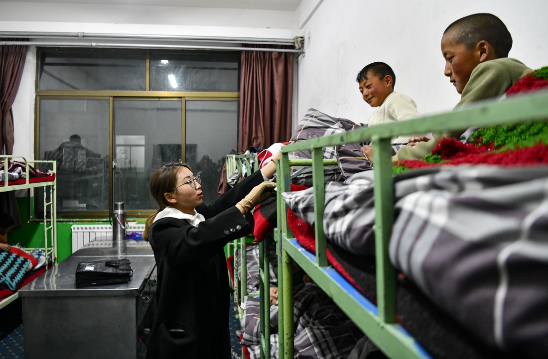 扎西宗乡完全小学的值班老师在检查孩子睡觉时是否盖好被子（6月5日摄）。新华社记者 晋美多吉 摄