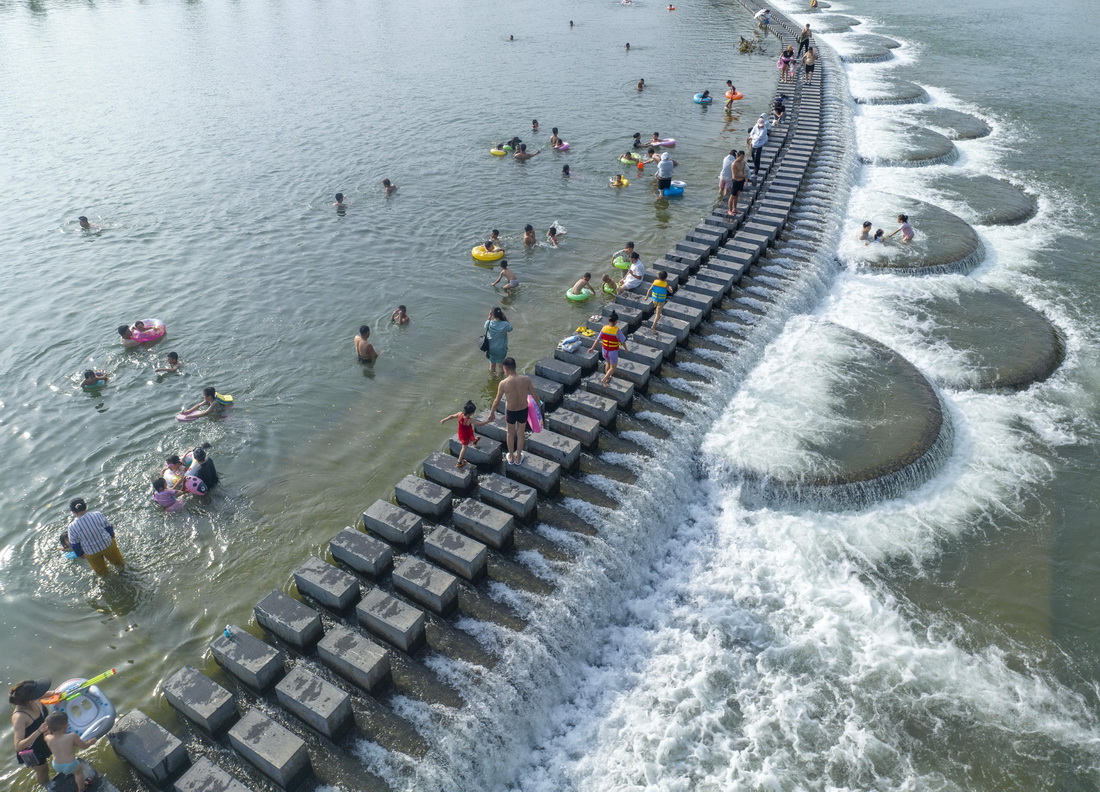 7月1日，在湖南省永州市道縣梅花鎮貴頭村，人們在洑水河裡享受清涼（無人機照片）。新華社發（蔣克青攝）