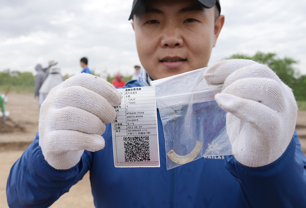7月5日，考古隊工作人員在發掘現場展示出土文物和對應的信息標簽。新華社記者 李賀 攝