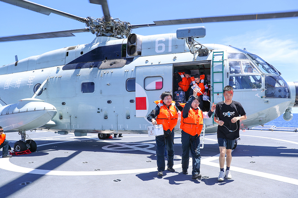 當地時間7月6日上午，中國海軍“和平方舟”號醫院船在西太平洋某海域開展全要素、全流程海空立體醫療救護演練。這是醫護人員搭乘艦載直升機接護“傷員”。新華社發（黎宇 攝）