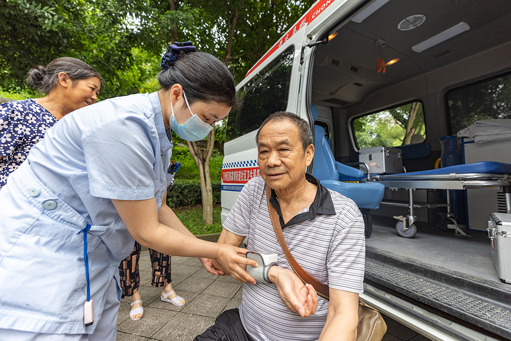 7月14日，在重慶市萬州三中江南校區臨時安置點內，醫護人員為轉移安置人員測量血壓。新華社記者 黃偉 攝