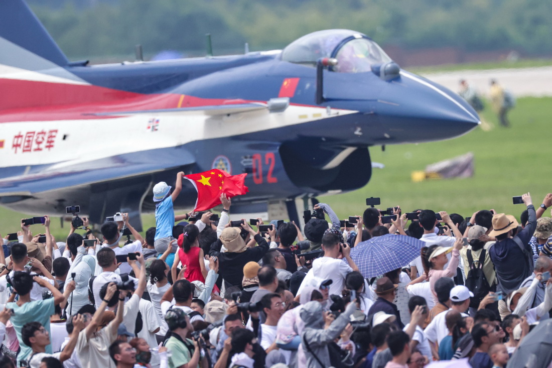 7月27日，在空軍航空開放活動·長春航空展首個公眾日，觀眾高舉國旗與飛行員互動。新華社發（譚巳成攝）