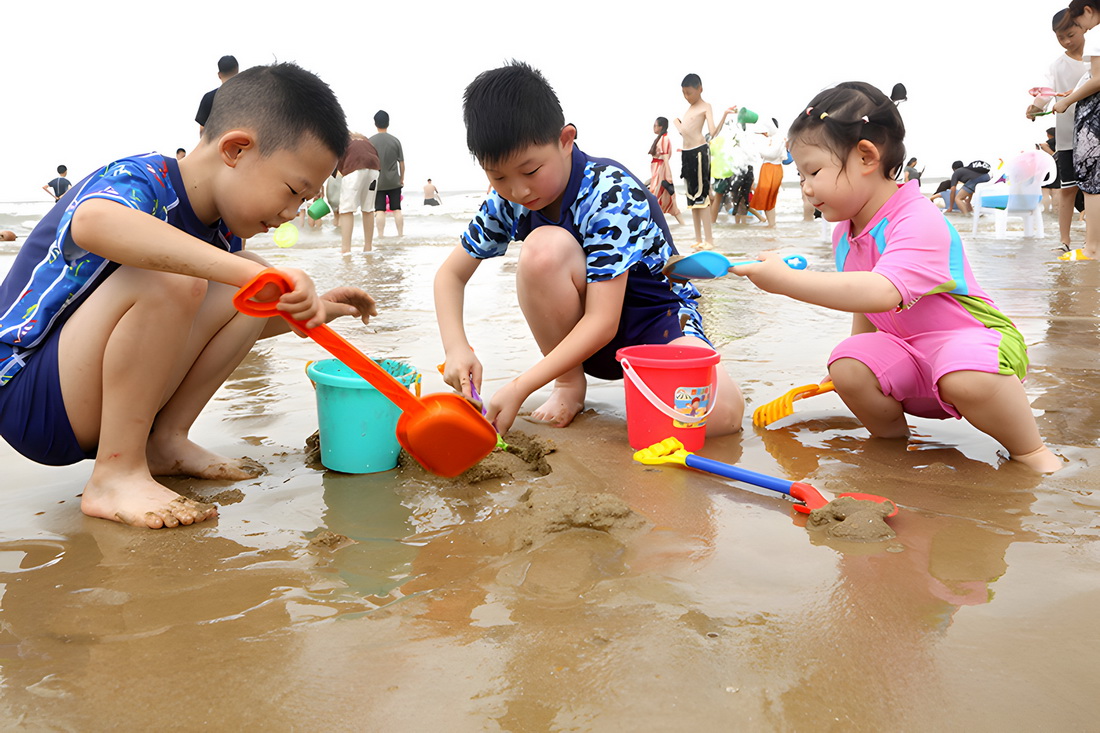 7月29日，小朋友們在江蘇省連雲港市連島景區大沙灣海濱浴場沙灘上玩沙子。新華社發（王春 攝）