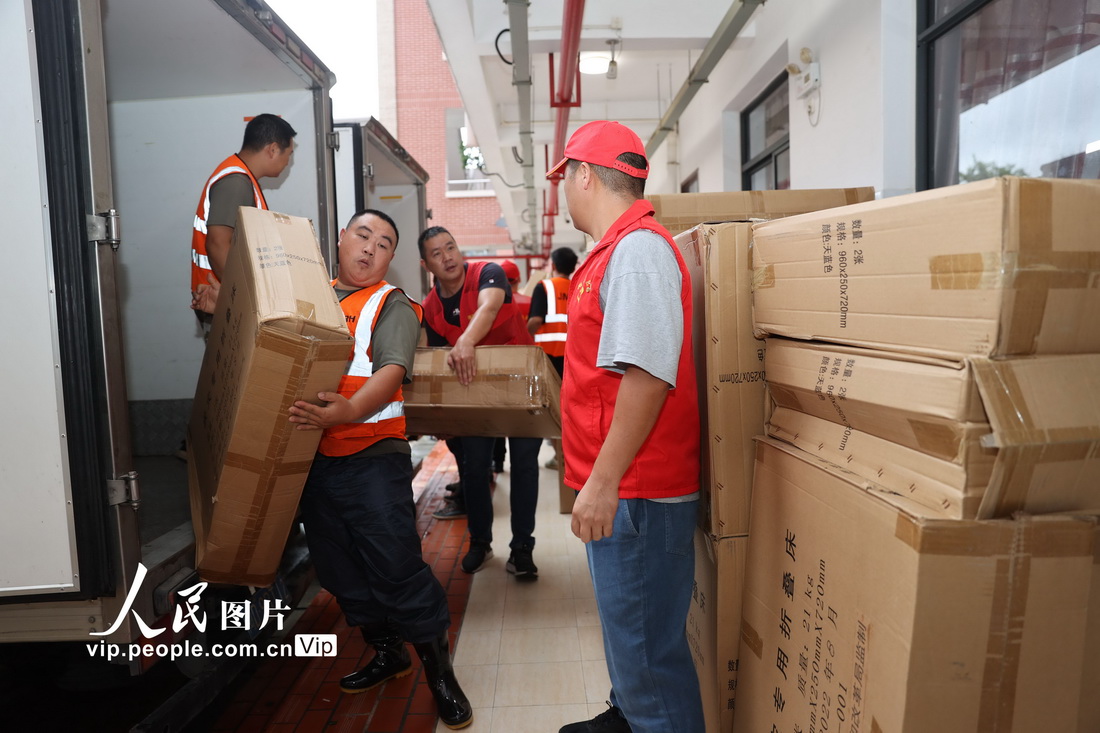 7月29日，在福建省廈門市新圩學校臨時安置點，志願者在搬運物資。