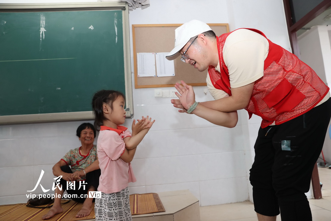 7月29日，在福建省廈門市新圩學校臨時安置點，志願者與受災轉移安置的小朋友在互動。