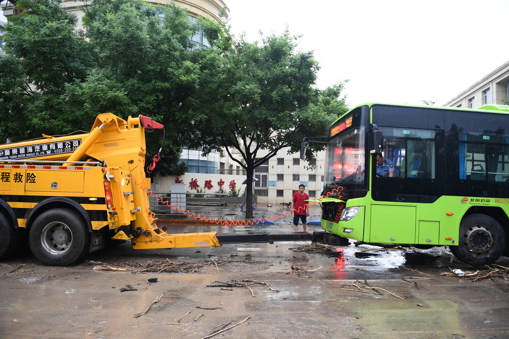 7月31日，抢险人员在北京市门头沟区新桥大街救援抛锚的公交车。新华社记者 鞠焕宗 摄