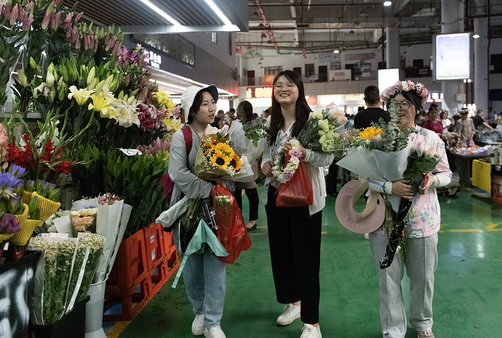 幾名外地游客在昆明斗南花卉市場內購買鮮花（7月13日攝）。新華社記者 陳欣波 攝