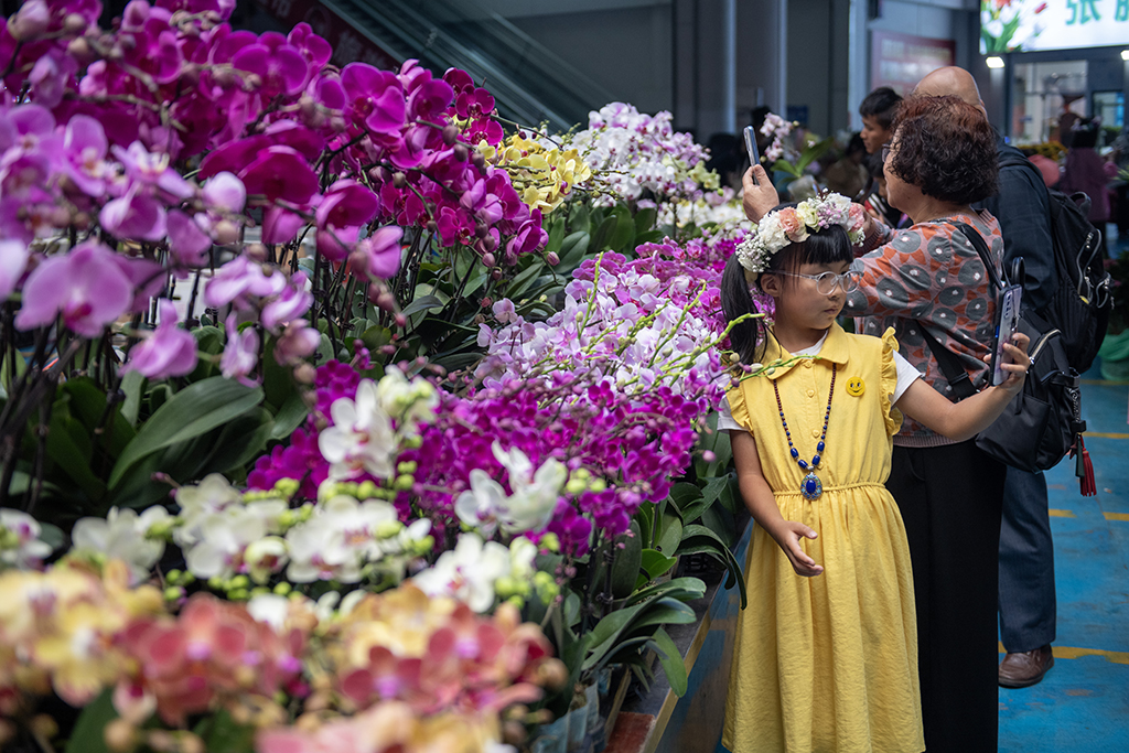 小朋友在昆明斗南花卉市場內的鮮花旁自拍（7月13日攝）。新華社記者 陳欣波 攝