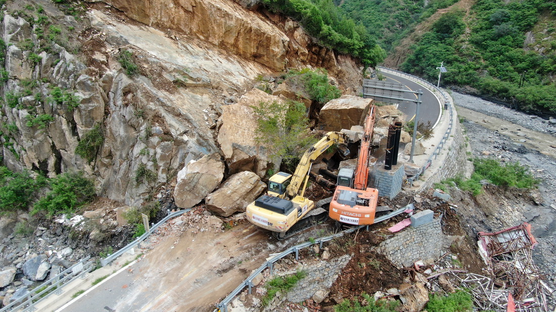 8月6日，在北京市房山區史家營鄉金雞台村附近，北京建工機施集團的大型機械設備在清理阻斷道路的落石（無人機照片）。