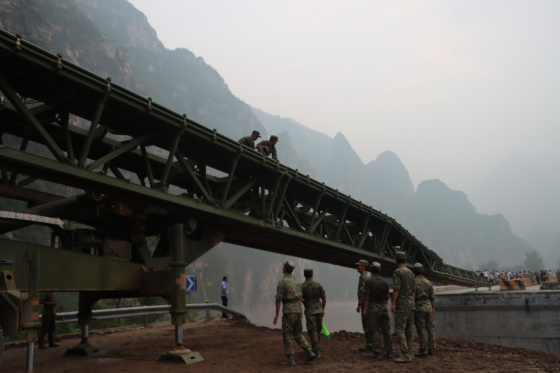 8月3日，中部战区陆军第82集团军某旅在北京市房山区涞宝路四渡桥断桥处架设桥梁，官兵们在推送桥体。新华社发（张康 摄）