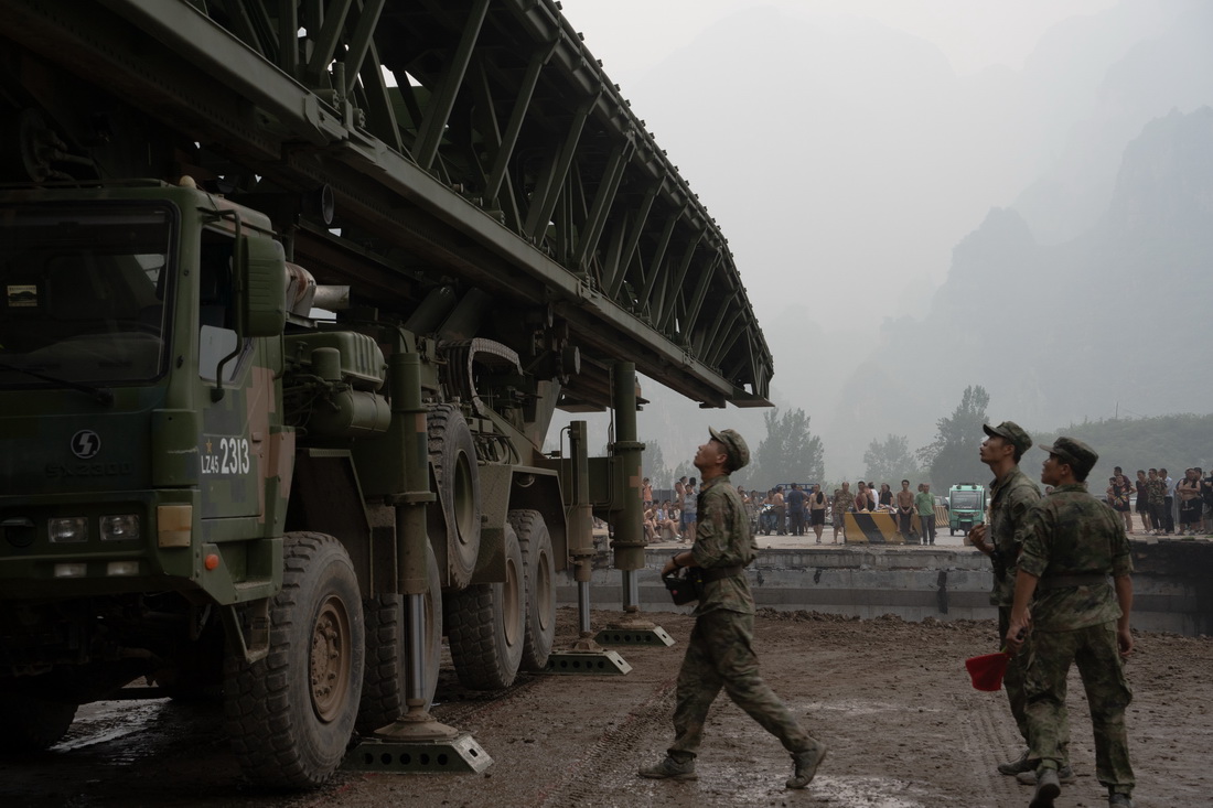 8月3日，中部战区陆军第82集团军某旅在北京市房山区涞宝路四渡桥断桥处架设桥梁，官兵们在对接桥体。新华社发（庞鑫 摄）