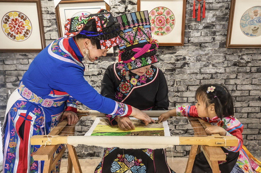 陳雲珍的小孫女看外婆和媽媽繡制作品。皇甫玉蓉攝