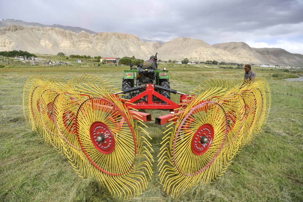 在新疆塔什库尔干塔吉克自治县瓦恰乡，牧民调试收割牧草的机械（8月28日摄）。