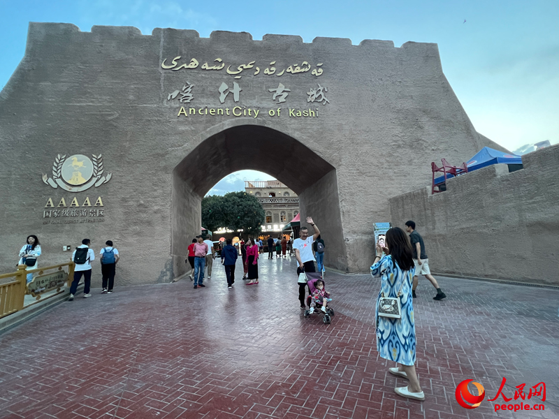 夜幕降临，游客在喀什古城大门拍照留念。人民网记者 常雪梅摄