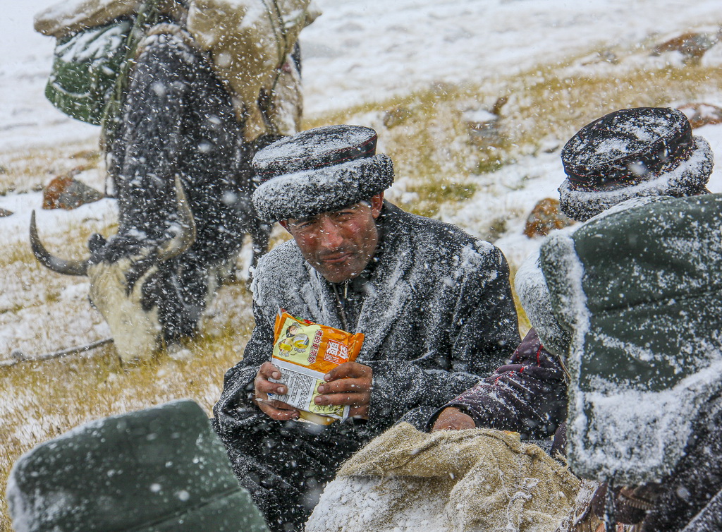 2010年9月24日，拉齊尼在邊境線巡邏時，冒著風雪嚴寒在吃午飯。新華社發（王烈 攝）