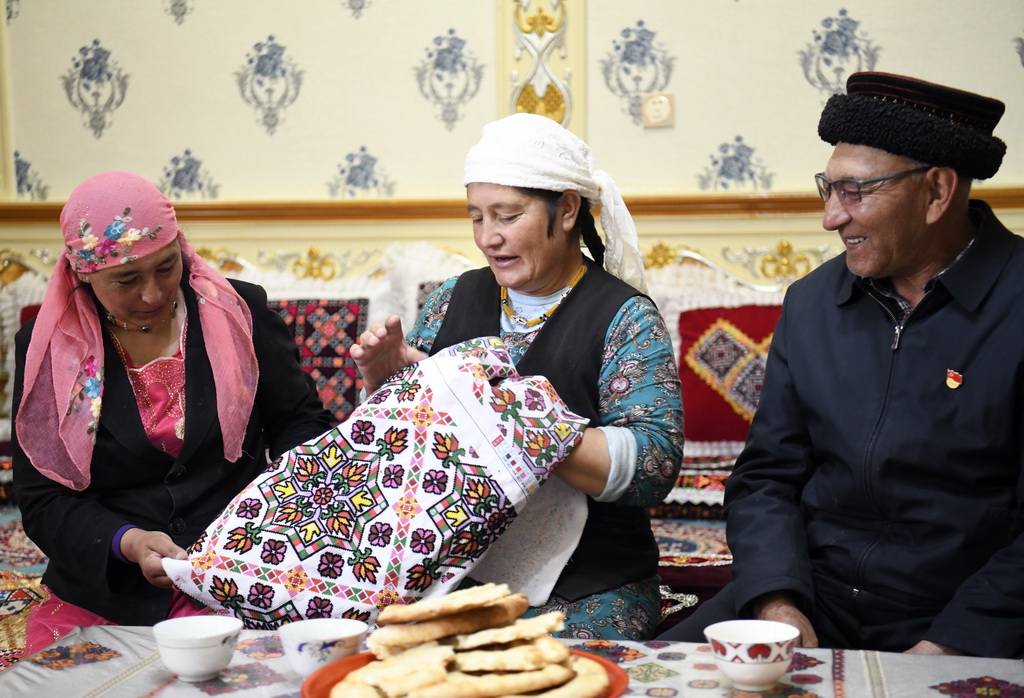 9月4日，巴依卡老人在家中休息，他的老伴帕熱扎·加依克（中）在繡制靠墊套。新華社記者 王菲 攝