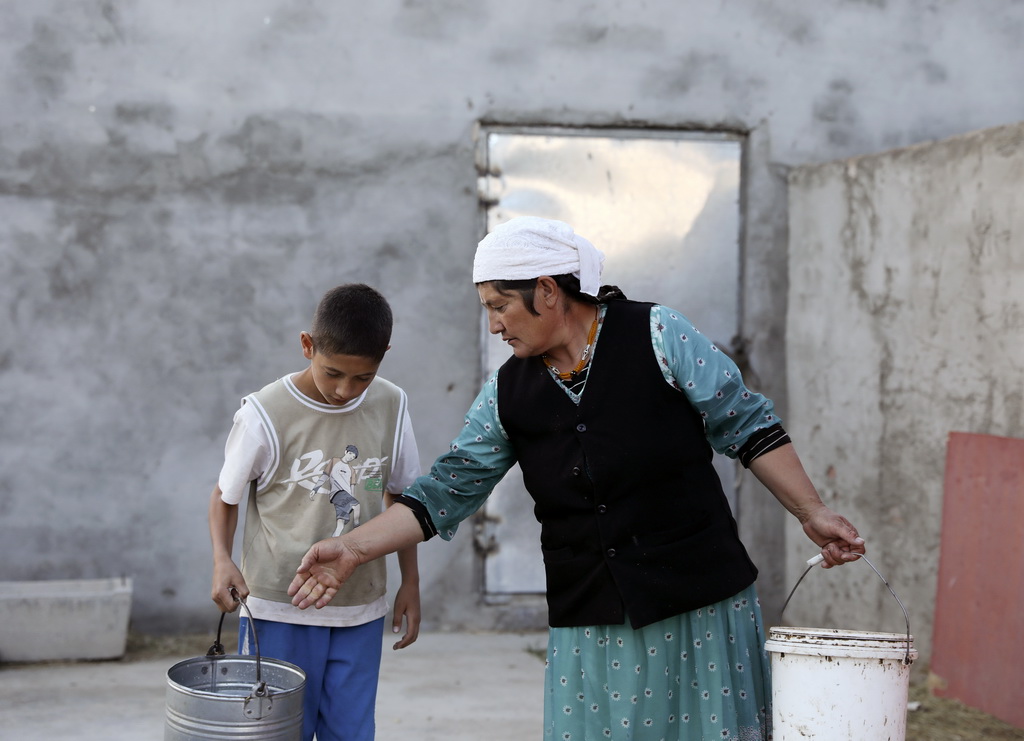 9月5日，巴依卡老人的小兒子熱飛·巴依卡替媽媽拿較重的牛奶桶。新華社記者 程婷婷 攝