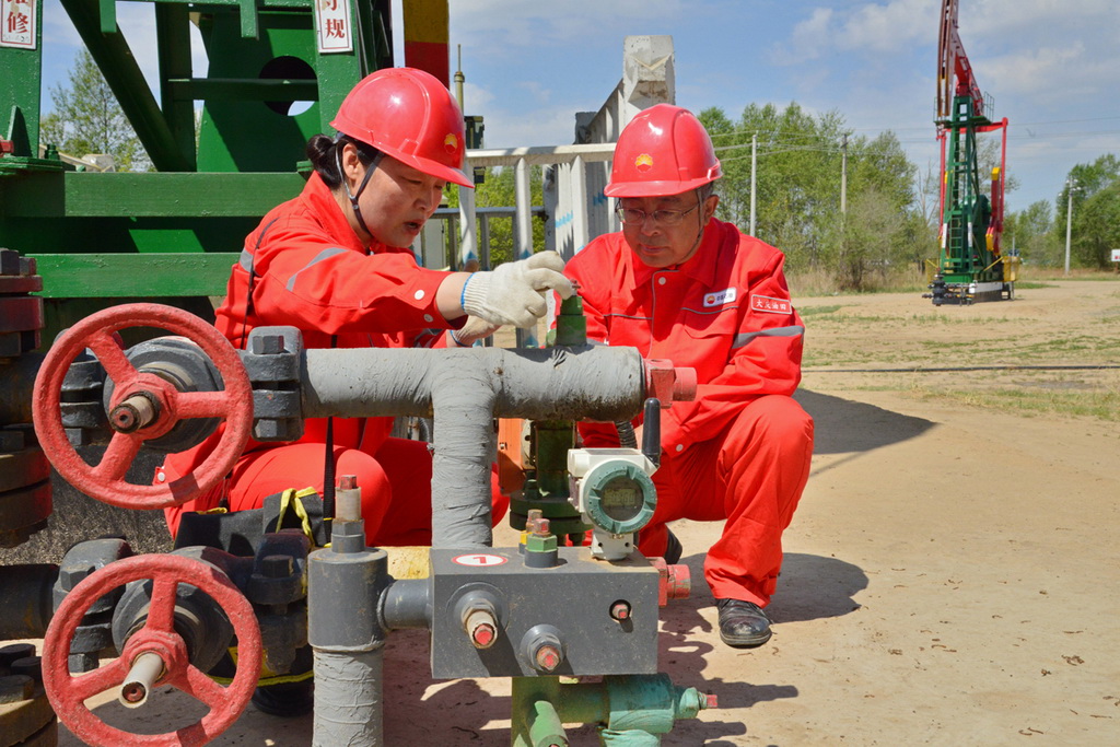 劉麗和採油48隊的員工在井口調試抽油機井摻水閥。劉博欣攝