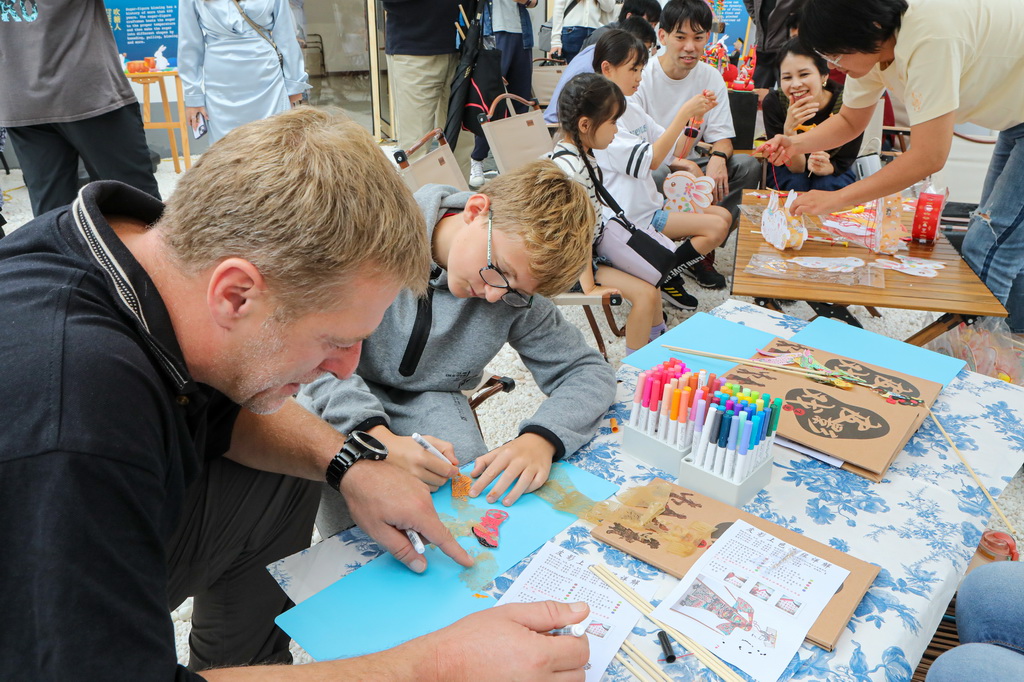 9月24日，在娄塘塌饼非遗传承馆，外国友人体验画皮影。