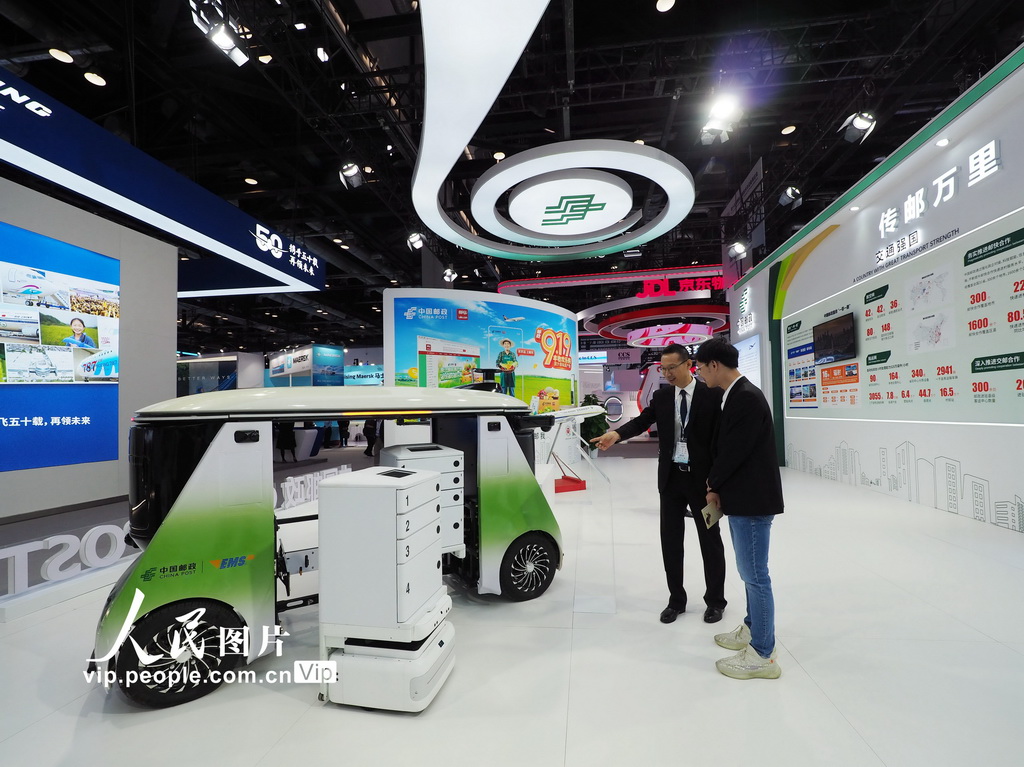 9月26日，北京国家会议中心，观众在第十五届国际交通技术与设备展览会中国邮政展位上参观无人车与楼宇终端投递机器人。