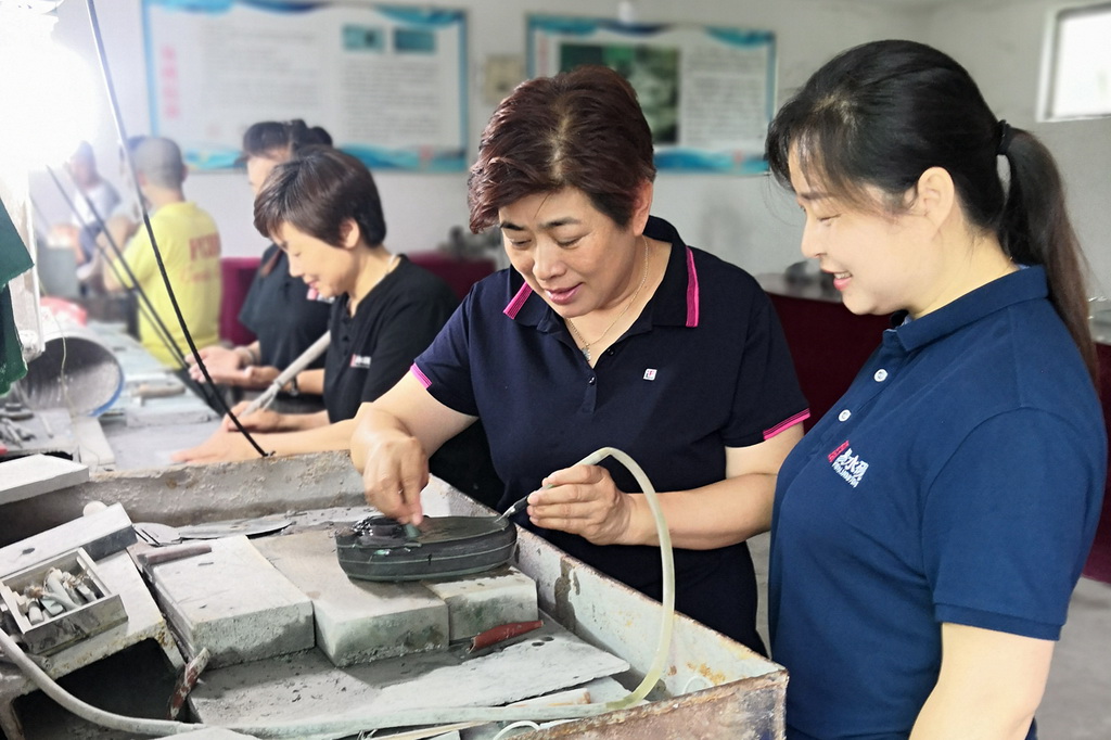 張淑芬在車間向下崗女工講解硯台雕刻方法。焦麗攝