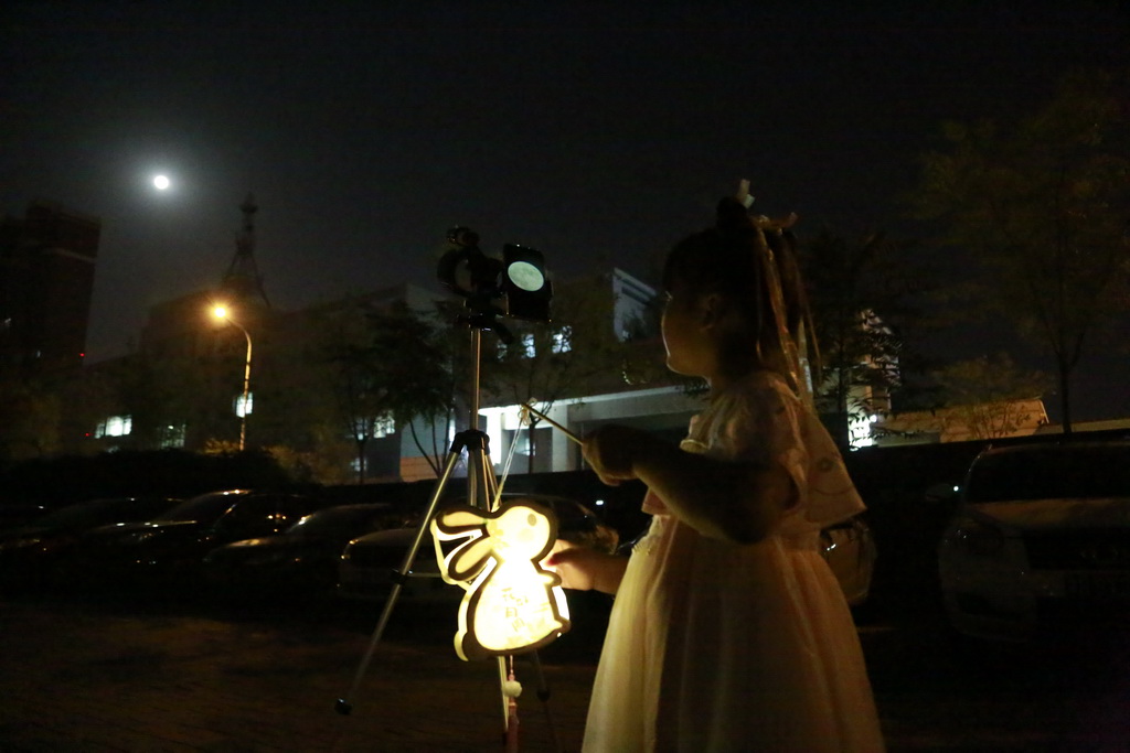 9月29日晚，在天津市津滨大道，一位身着汉服的小姑娘用天文望远镜观看月亮。人民网记者 崔新耀摄