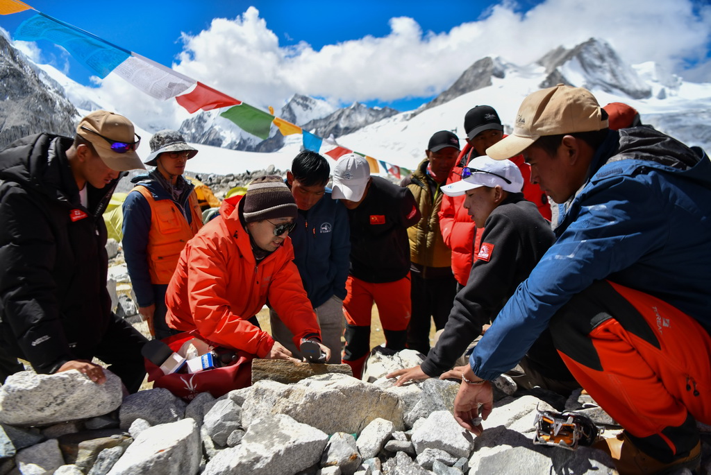 科考隊隊員褚楊（左三）在為西藏登山隊隊員講解如何採集峰頂至前進營地的岩石樣本（9月27日攝）。