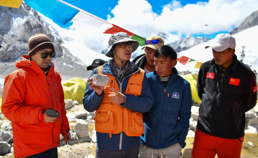 科考隊隊員劉小馳（左二）在為西藏登山隊隊員講解如何採集峰頂至前進營地的岩石樣本（9月27日攝）。