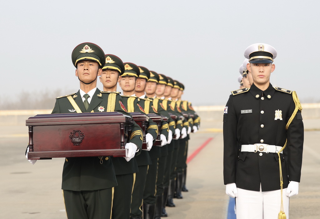 11月23日，在韓國仁川國際機場，中國人民解放軍禮兵（左）從韓方接過中國人民志願軍烈士棺槨。新華社記者 曹燦 攝