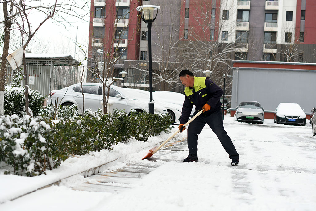 2023年12月11日，北京迎來降雪，石景山某小區，物業工作人員正在清理積雪。人民網記者 於凱攝