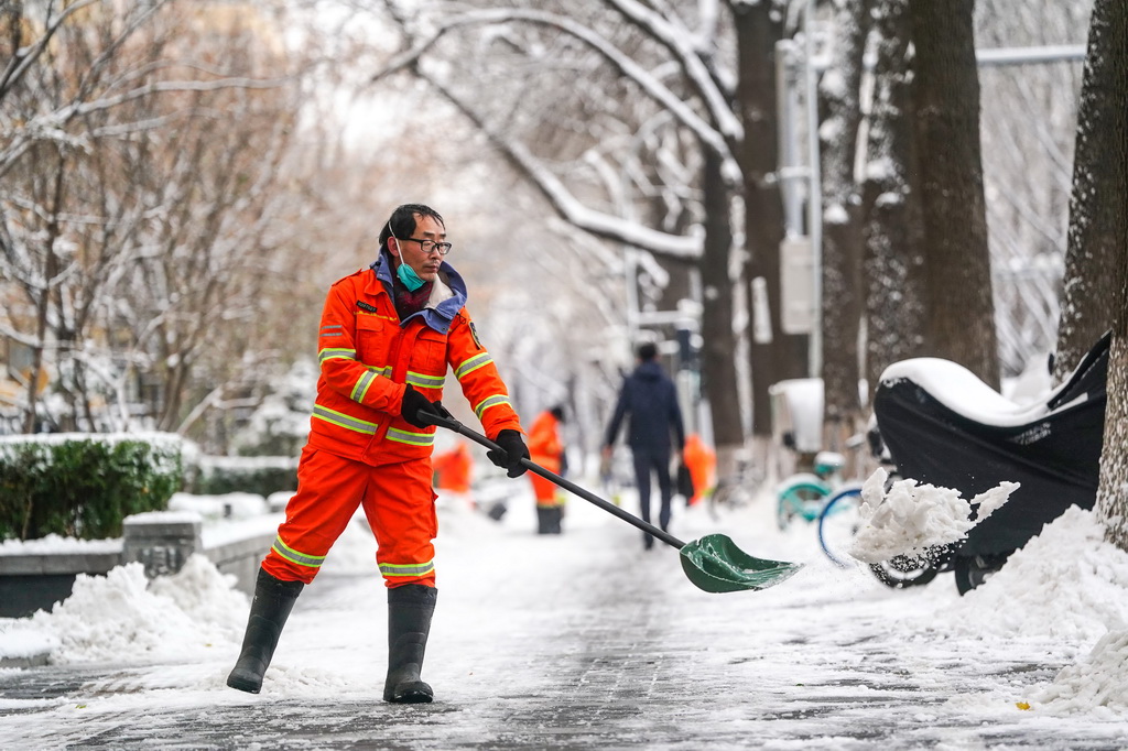 12月11日，環衛工人在雪后的北京前門西大街清理人行道上的積雪。新華社記者 陳曄華 攝