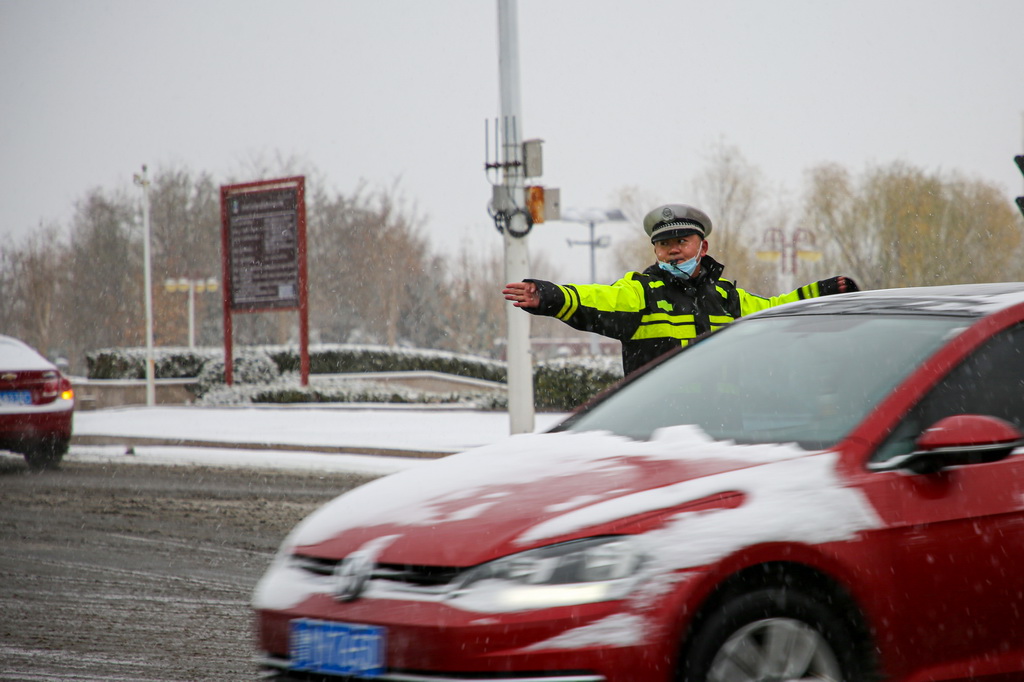 12月11日，在山東省濱州市沾化區，交警在雪中引導車輛有序通行。新華社發（賈海寧 攝）