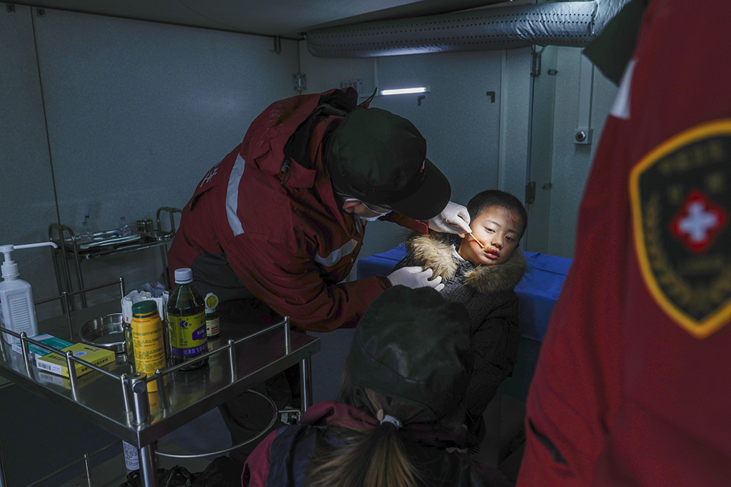 12月19日，在甘肅臨夏積石山縣大河家鎮大河村安置點，甘肅省人民醫院的醫生在移動手術車上為小朋友清理傷口。新華社記者 方欣 攝