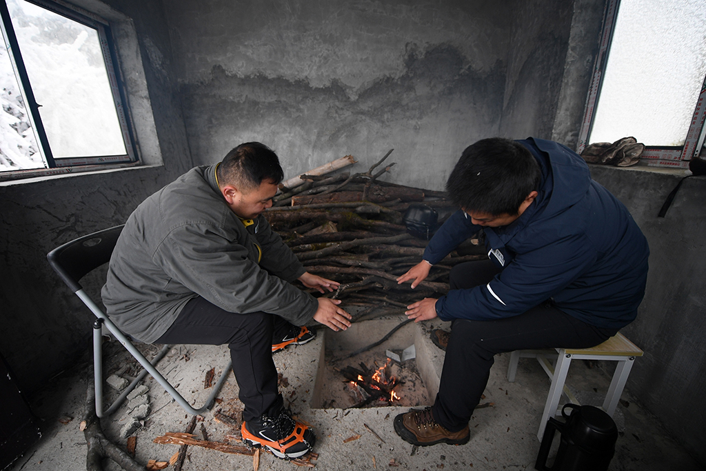 12月19日，尹斌（右）和龍昱君在110千伏西公線003號監測哨所休息。這座水泥小屋在2020年修建，以便輸電運檢工觀測融冰時休息。新華社記者 陳振海 攝