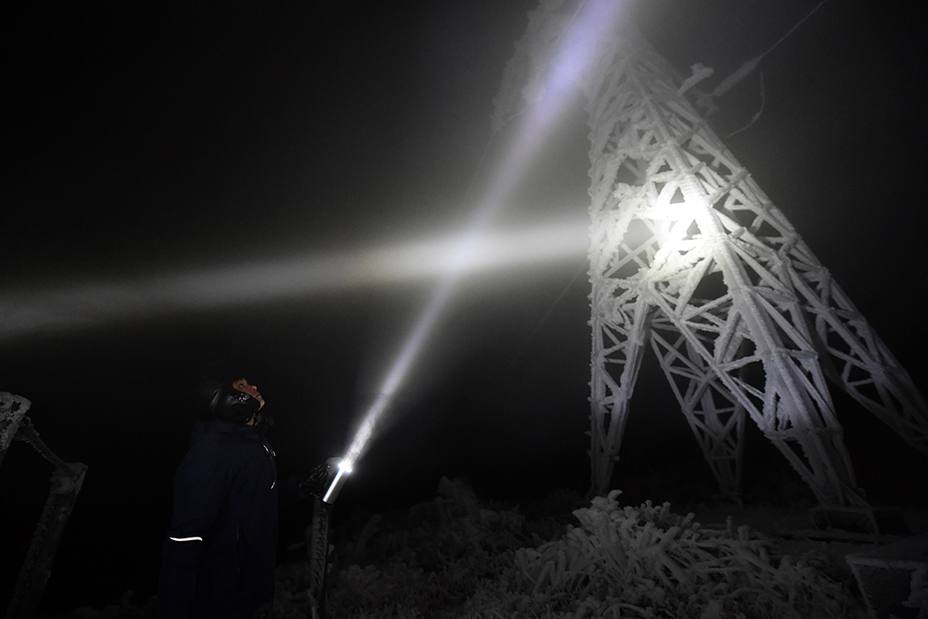 12月18日夜間，尹斌和龍昱君在110千伏西公線001號監測哨所觀測鐵塔覆冰情況。新華社記者 陳振海 攝