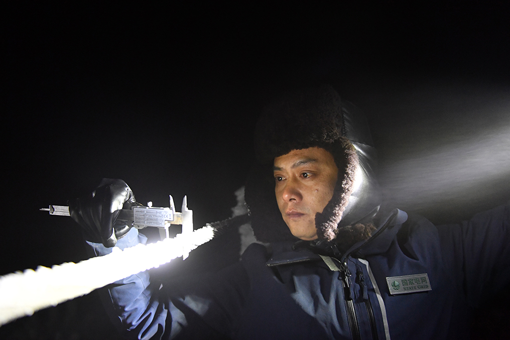 12月18日夜間，尹斌在110千伏西公線001號監視哨所用游標卡尺測量導線覆冰厚度。新華社記者 陳振海 攝