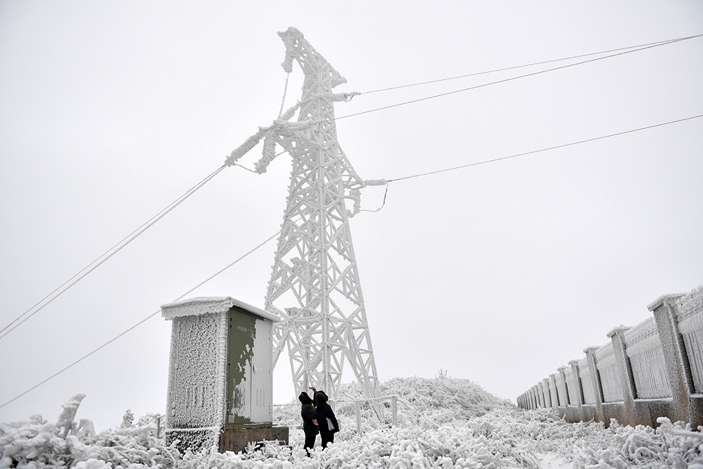 12月18日，尹斌和龍昱君在110千伏西公線001號監測哨所觀測鐵塔和導線的覆冰情況。新華社記者 陳振海 攝