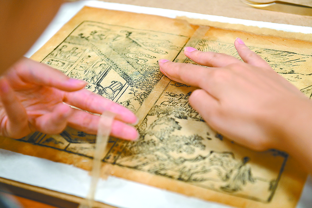國家圖書館，工作人員在修復破損古籍書葉中縫。