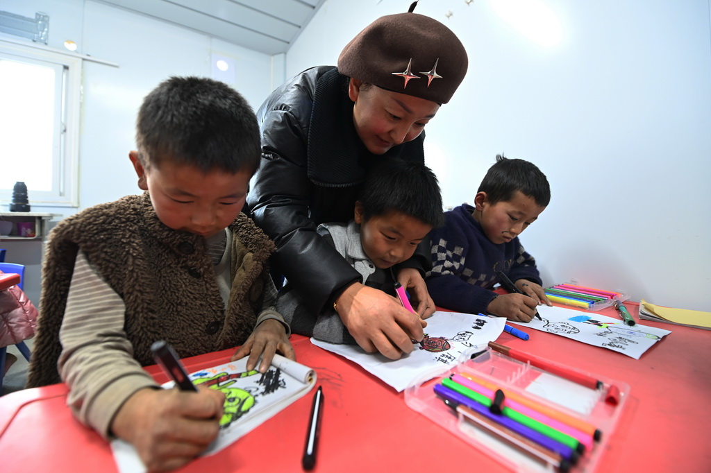 12月27日，在積石山縣大河家鎮梅坡小學臨時教學點，老師指導小學生畫畫。