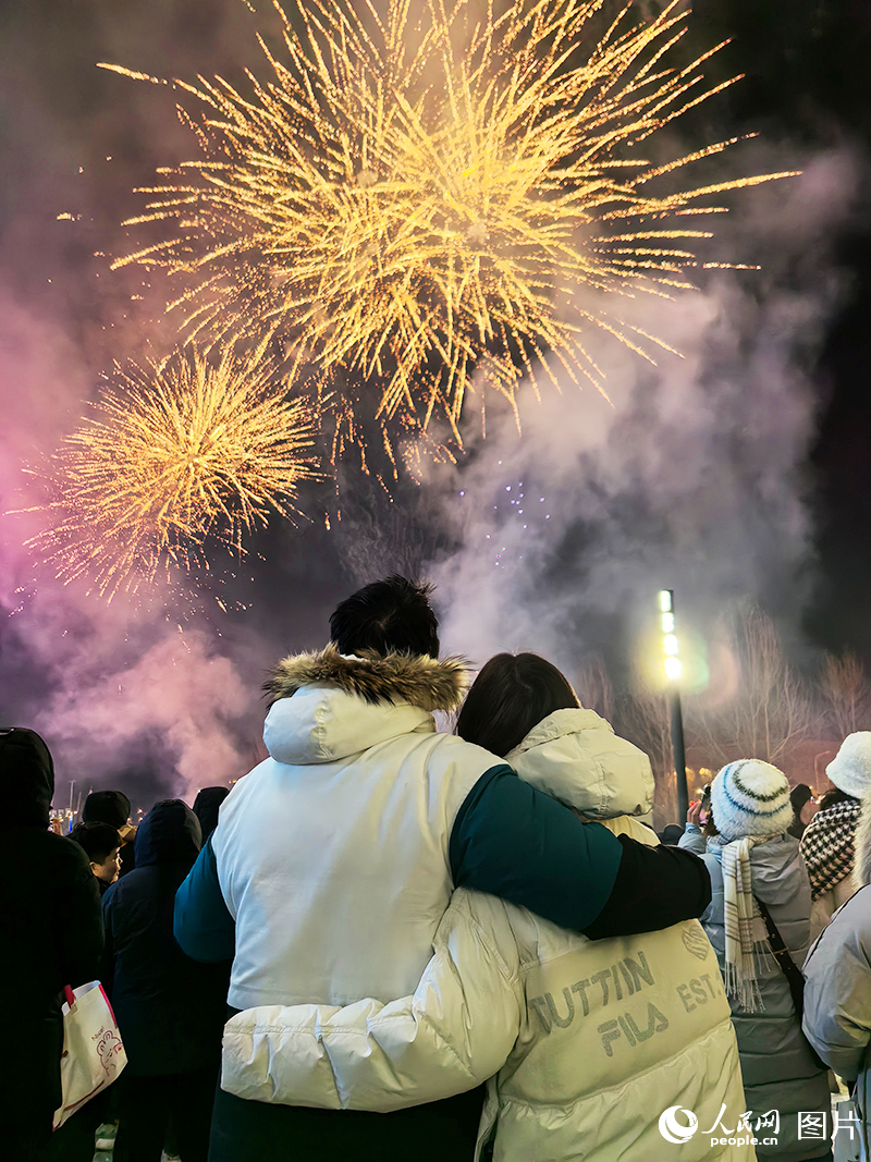 2023年12月31日晚，在吉林長春街頭，一對情侶相互依偎，對著高空綻放的煙花許下新年心願。人民網記者 王海躍攝